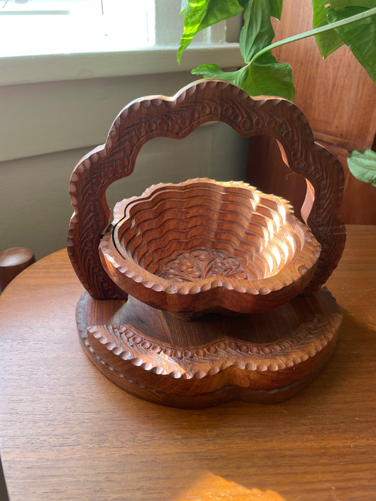 Carved wooden basket on a wooden surface with a plant in the background