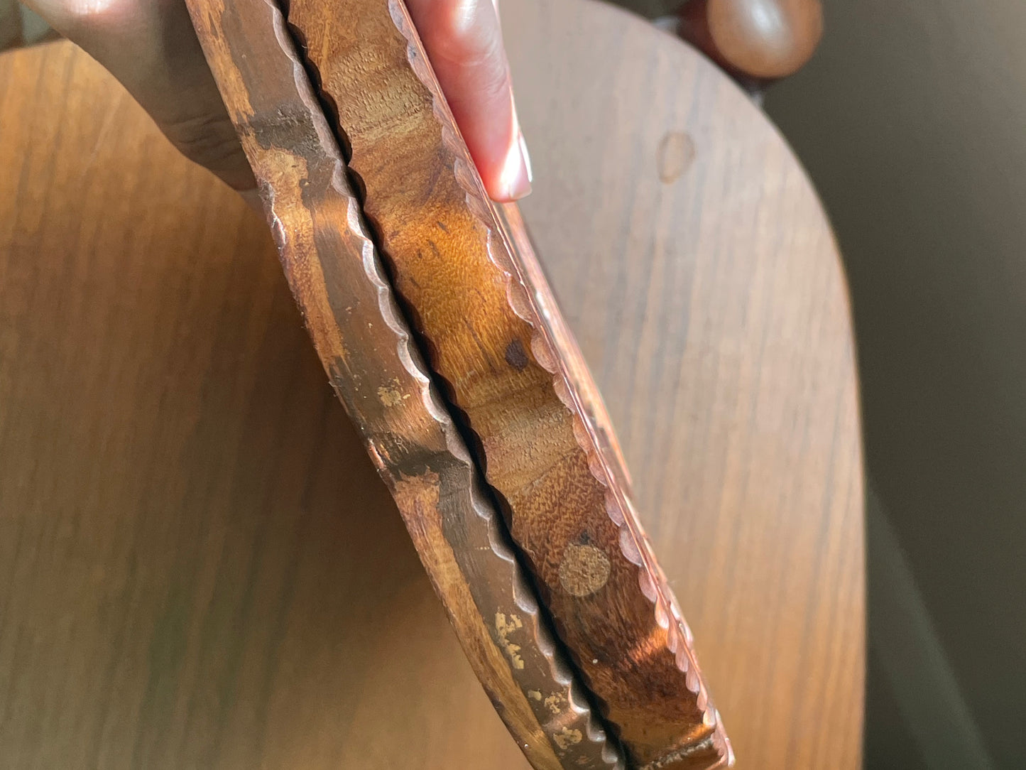 Close-up of the worn edge of a wooden object on a wooden surface.