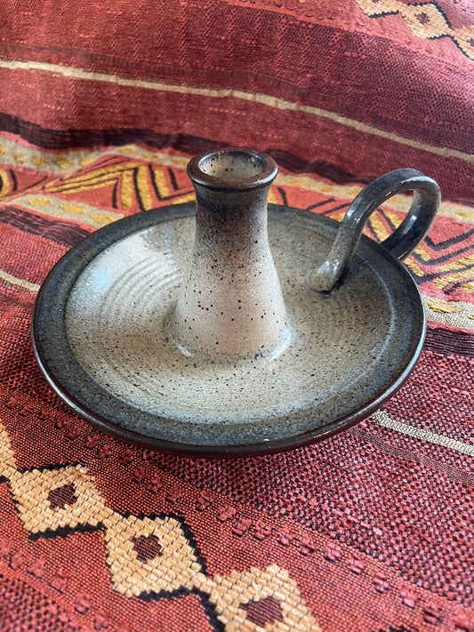 Ceramic candle holder on a Southwest patterned fabric background.