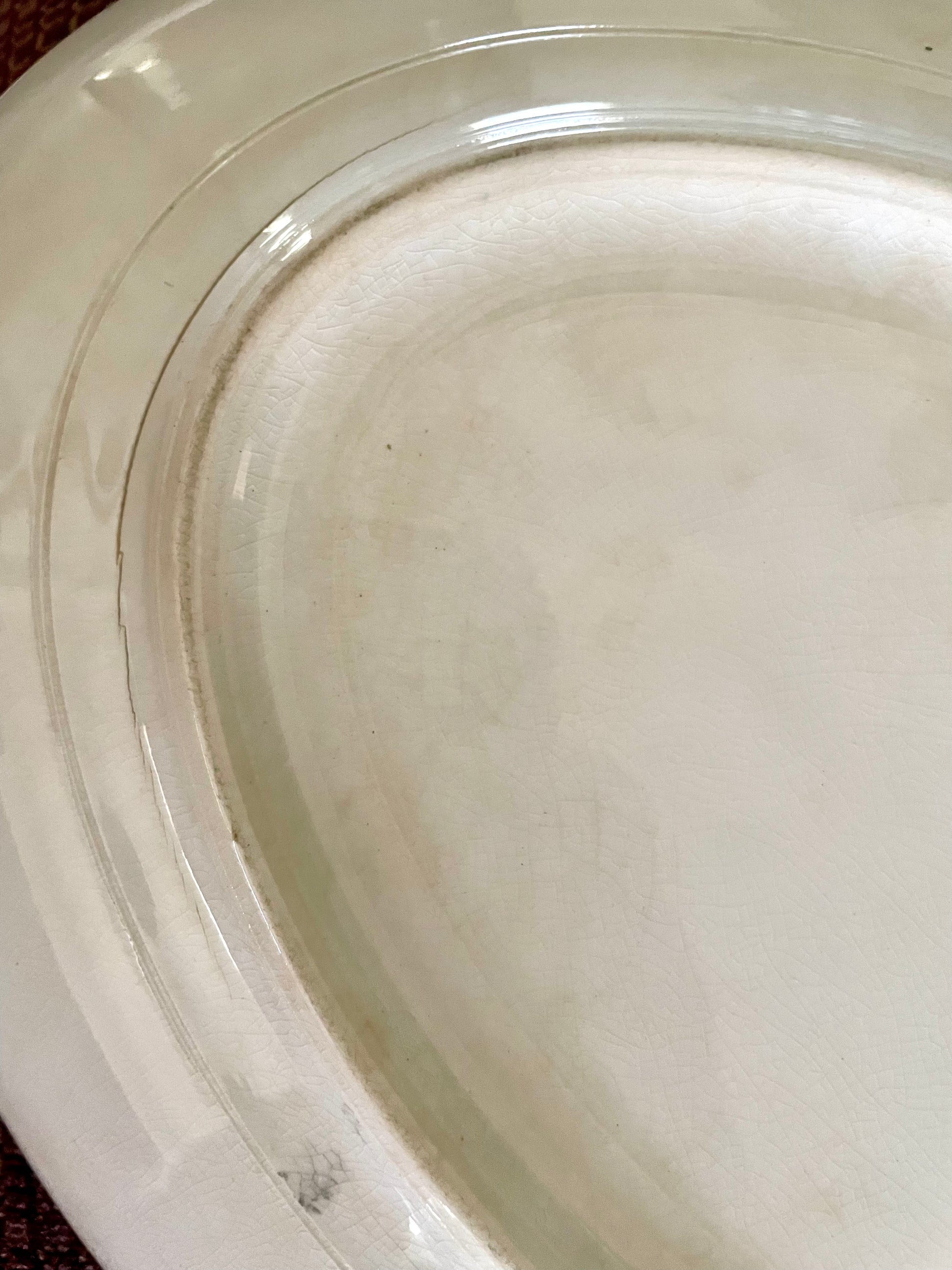 Close-up of the inside bottom of a white porcelain plate, showing some staining and crazing.