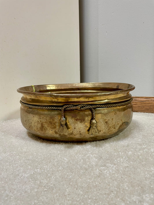 Brass pot with hammered texture and faux ropes with tassels knotted at the front.