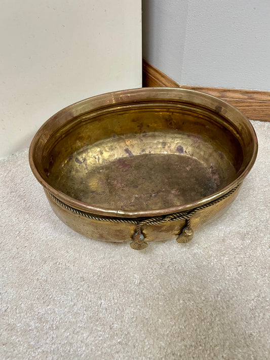 View of oval-shaped brass pot from above showing hammered texture and faux ropes with tassels knotted at the front.