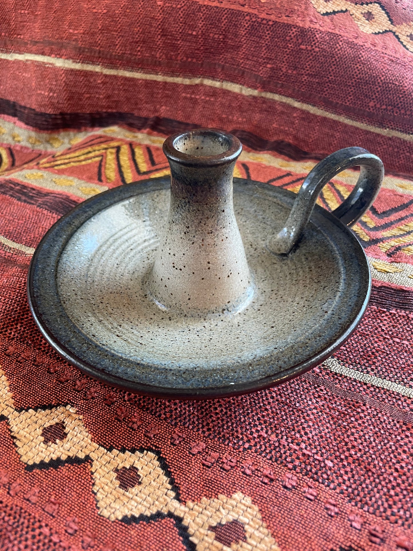 Ceramic candle holder on a Southwest patterned fabric background.