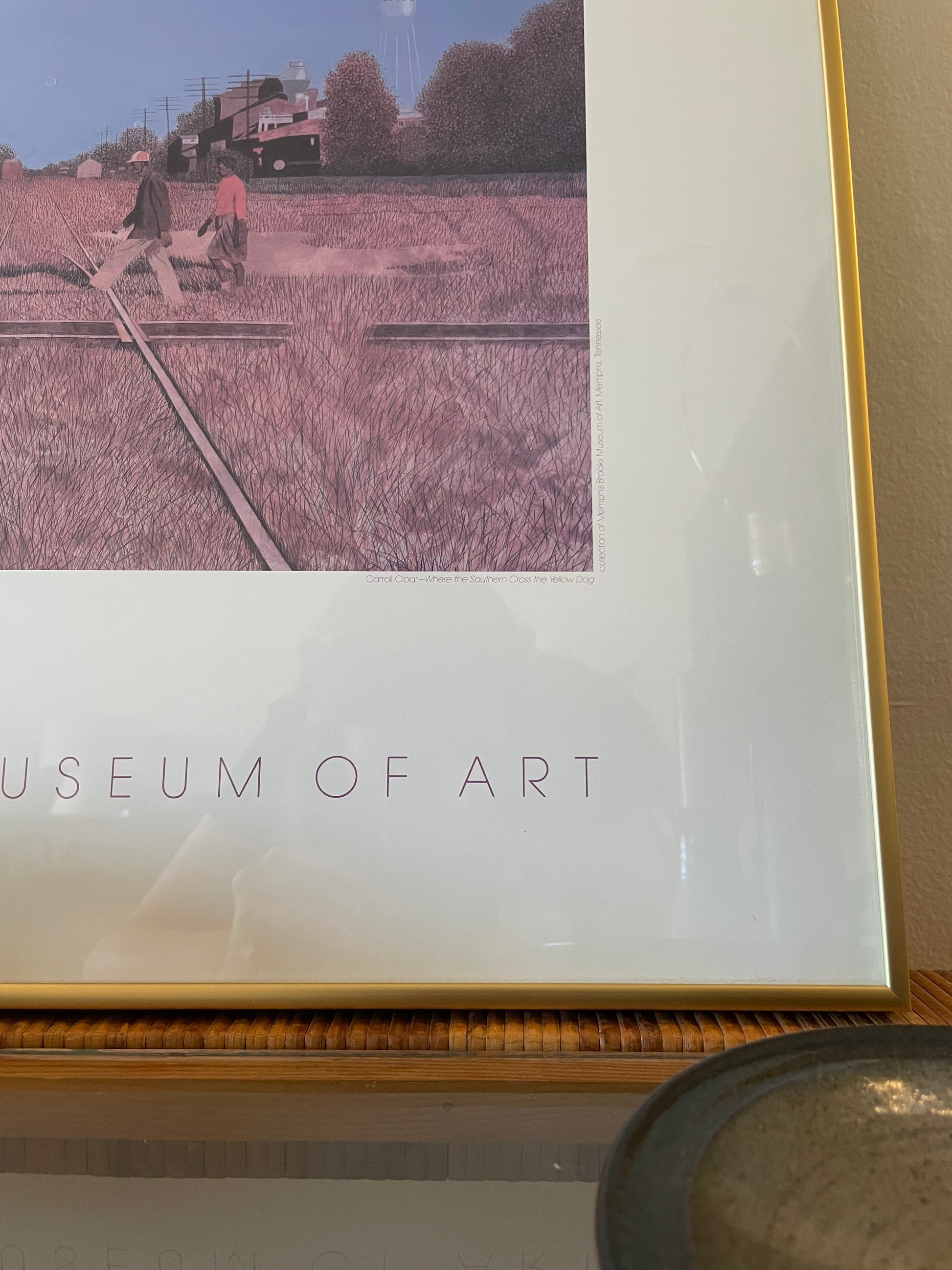 A framed art print in a gold frame, featuring a sketch-like illustration of a field with a train track and two walking figures and with the text 'MUSEUM OF ART' partially visible at the bottom.
