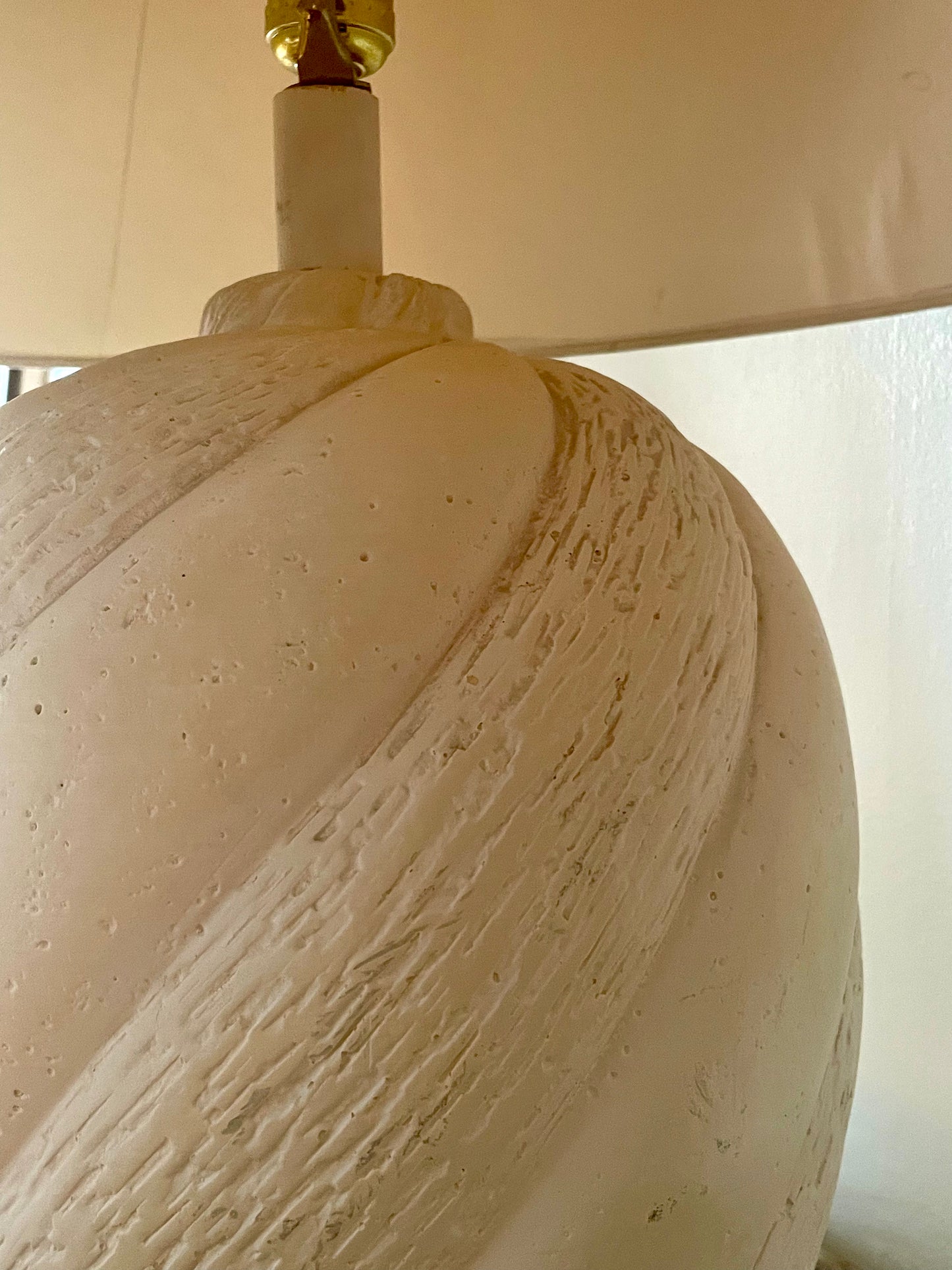 Close-up of a cream-colored textured plaster table lamp base with a brass harp.