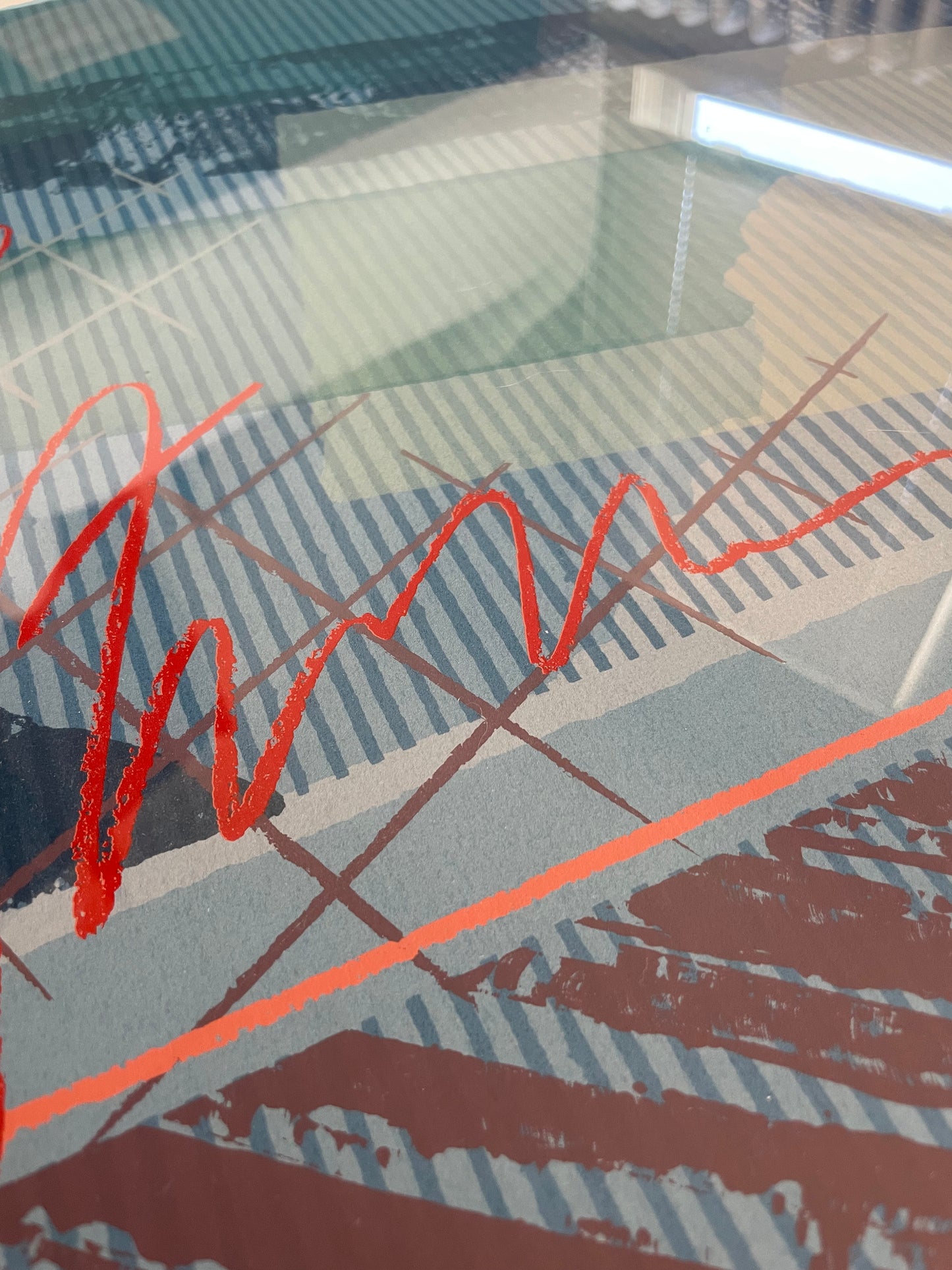 Closeup of an abstract art print featuring a bold red scribble and geometric patterns in gray, blue, and mauve tones.