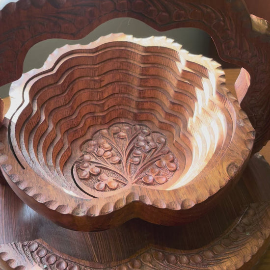 Video of carved wooden tiered basket collapsing into a trivet.