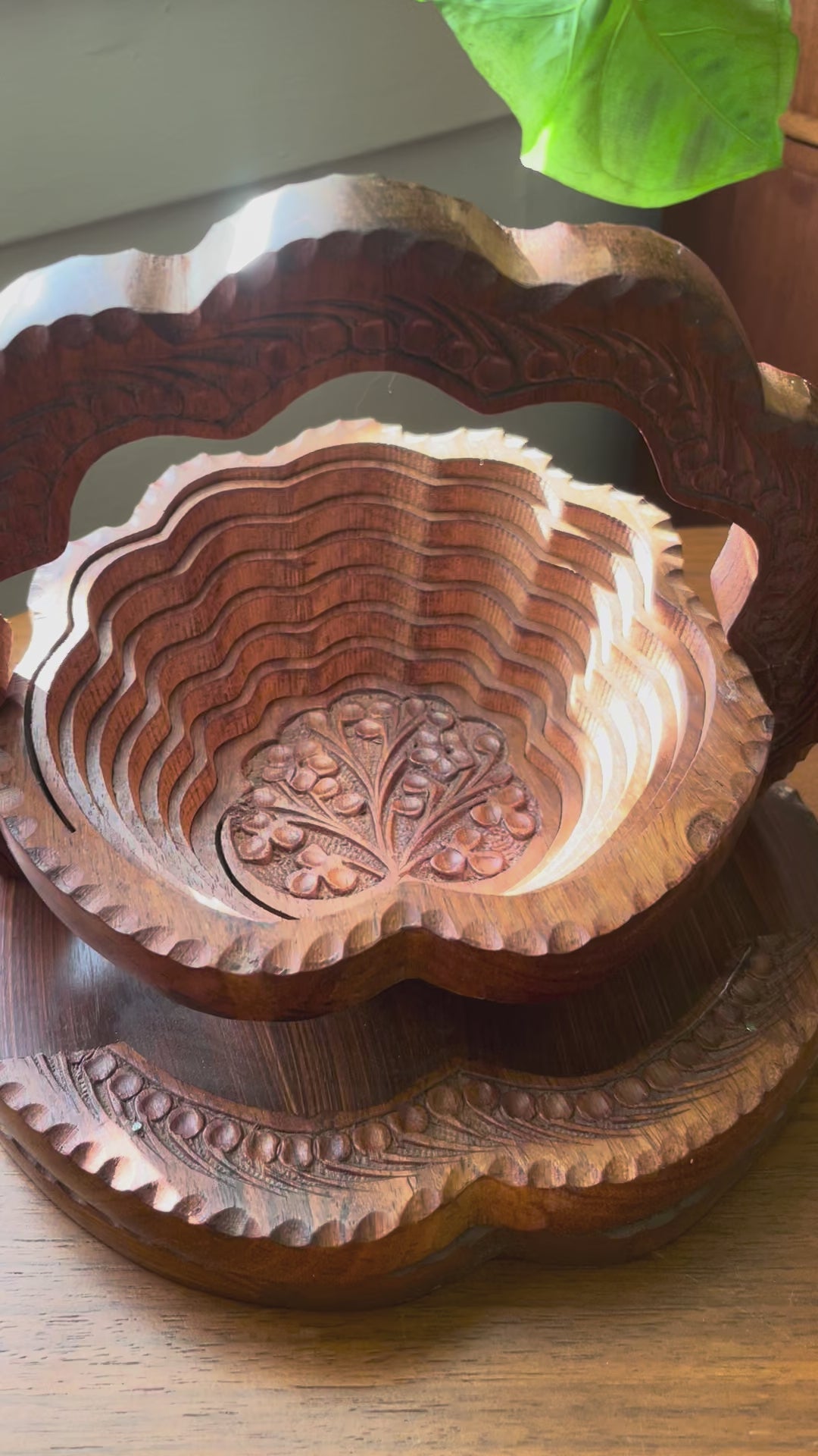 Video of carved wooden tiered basket collapsing into a trivet.