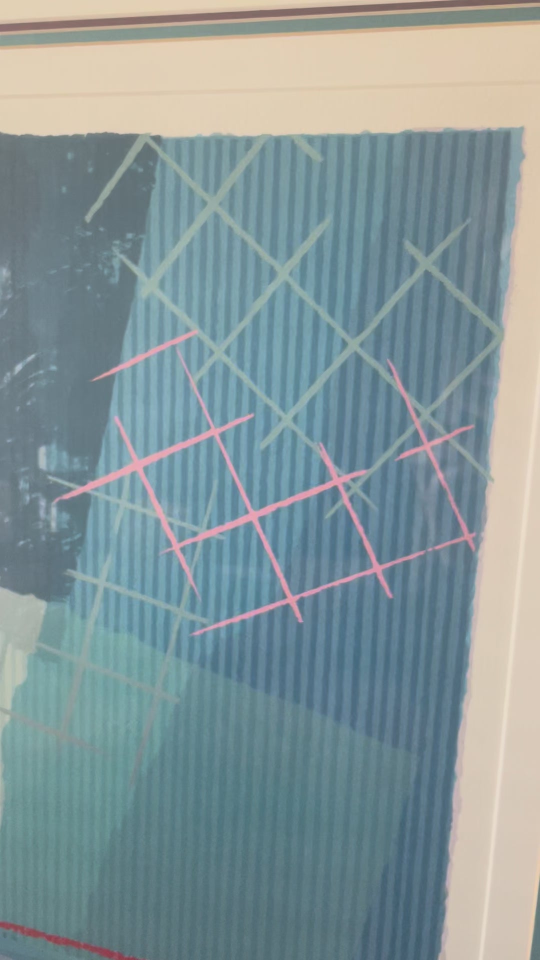Video showing closeup scan of a framed abstract art print. The artwork features a complex composition of blue, teal, red, pink and mauve geometric patterns, enclosed in a white mat and a dark teal frame.